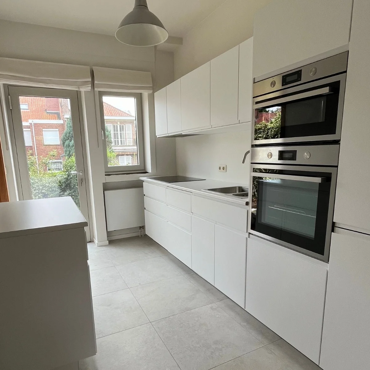 Moderne witte keuken met geïntegreerde ovens en inductiekookplaat