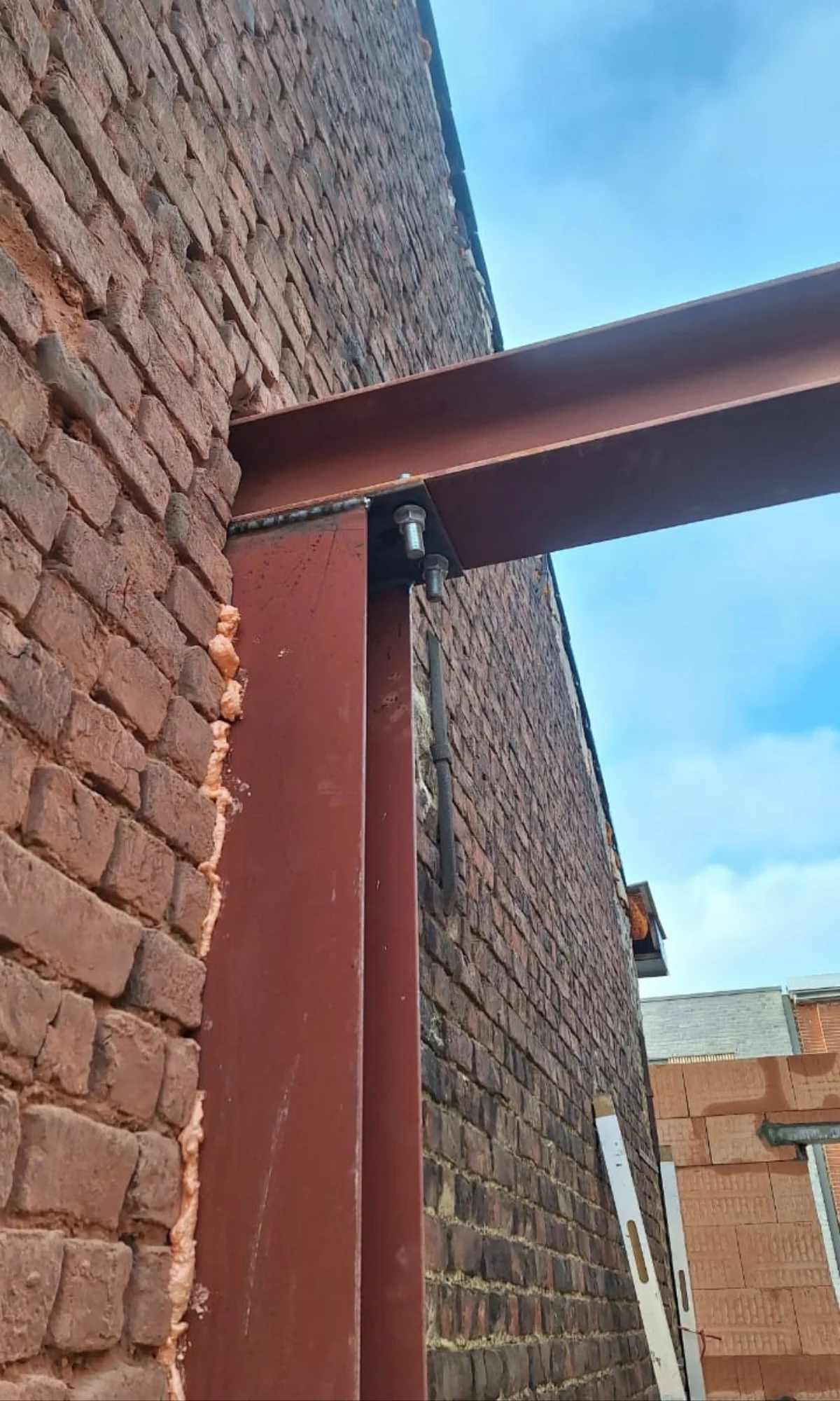 Structurele uitbreiding met stalen ligger en kolom in een baksteenmuur